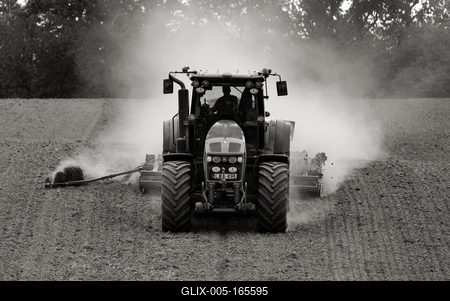A farmer working on the field with a John Deere tractor. Black and white.-stock-foto