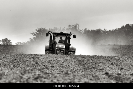 A farmer working on the field with a John Deere tractor. Black and white.-stock-foto