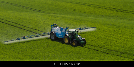 A farmer spraying on the spring wheat field with a John Deere tractor and a mamut topline sprayer.-stock-foto