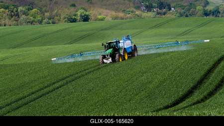 A farmer spraying on the spring wheat field with a John Deere tractor and a mamut topline sprayer.-stock-foto