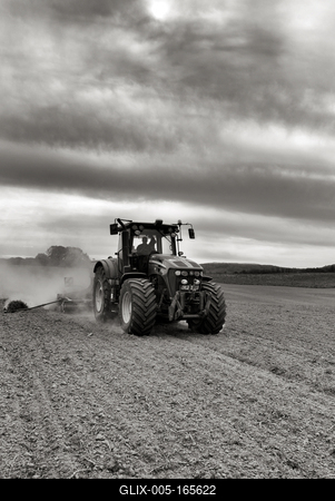 A farmer working on the field with a John Deere tractor. Black and white.-stock-foto