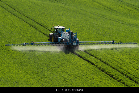 A farmer spraying on the spring wheat field with a John Deere tractor and a mamut topline sprayer.-stock-foto