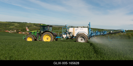 A farmer spraying on the spring wheat field with a John Deere tractor and a mamut topline sprayer. Panning shot.-stock-foto