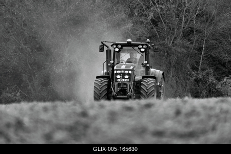 A farmer working on the field with a John Deere tractor. Black and white.-stock-foto
