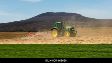 A farmer is plowing with a John Deere tractor. Sunny day on the field. It's a panning shot, that cause the blurry background and foreground.-stock-foto