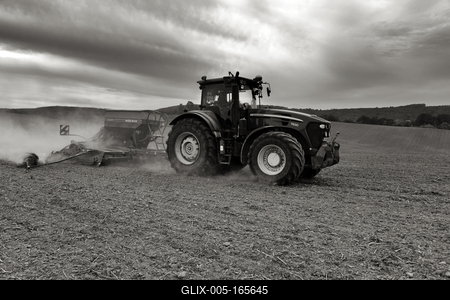 A farmer working on the field with a John Deere tractor. Black and white.-stock-foto