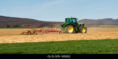 A farmer is plowing with a John Deere tractor. Sunny day on the field. It's a panning shot, that cause the blurry background and foreground.-stock-foto