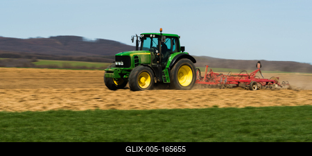 A farmer is plowing with a John Deere tractor. Sunny day on the field. It's a panning shot, that cause the blurry background and foreground.-stock-foto