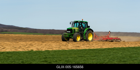 A farmer is plowing with a John Deere tractor. Sunny day on the field. It's a panning shot, that cause the blurry background and foreground.-stock-foto