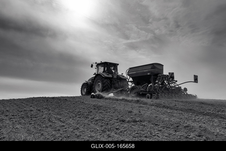A farmer sowing with a John Deere tractor and a Horsch Pronto 4dc seeding machine. Black and white.-stock-foto