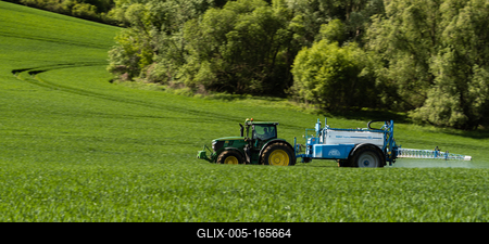 A farmer spraying on the spring wheat field with a John Deere tractor and a mamut topline sprayer. Panning shot.-stock-foto