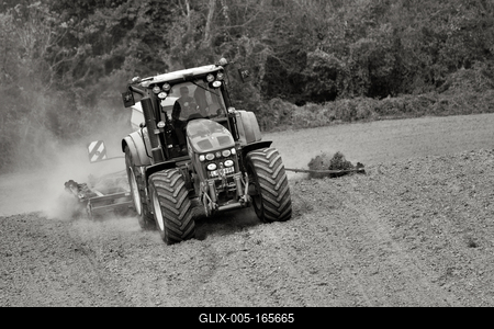 A farmer working on the field with a John Deere tractor. Black and white.-stock-foto