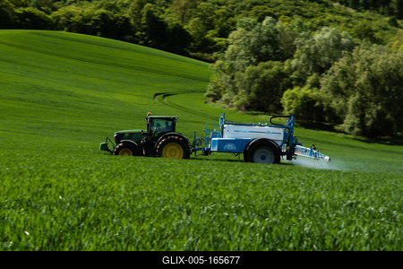 A farmer spraying on the spring wheat field with a John Deere tractor and a mamut topline sprayer. Panning shot.-stock-foto