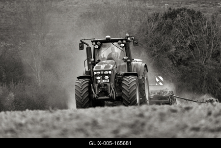 A farmer working on the field with a John Deere tractor. Black and white.-stock-foto