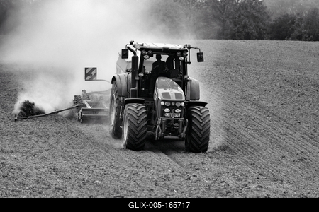 A farmer working on the field with a John Deere tractor. Black and white.-stock-foto