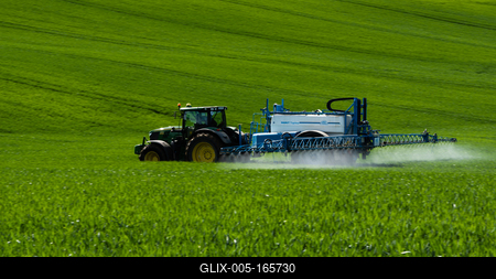 A farmer spraying on the spring wheat field with a John Deere tractor and a mamut topline sprayer. Panning shot.-stock-foto