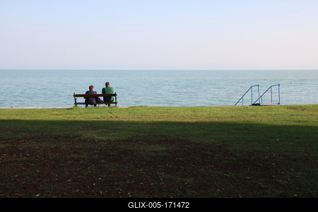 A woman and a man sitting on a bench by the lake.-stock-foto