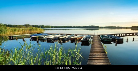 At the Schaalsee, wooden jetty with boats and reeds in the evening light, Schaalsee Biosphere Reserve, Mecklenburg-Western Pomerania, Germany-stock-foto