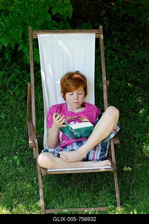 Child, boy, 11 years, reading a exciting holiday book whilst sitting in a deck chair in the garden-stock-foto