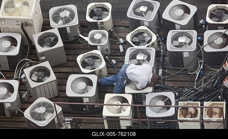 A man inspects air conditioning equipment on the roof of a building in the French Quarter, New Orleans, Louisiana, USA-stock-foto
