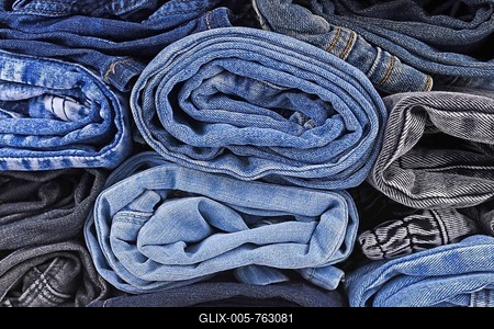 Different colored jeans pants rolled up in pile-stock-foto