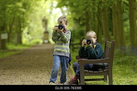 Ten and eight year old boys taking pictures in a park-stock-foto