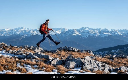 Mountaineer taking a big step, in front of mountain panorama, hiking trail at Guffertstein, in the background main ridge of the Alps with Großvenediger, in autumn, Brandenberg Alps, Tyrol, Austria-stock-foto