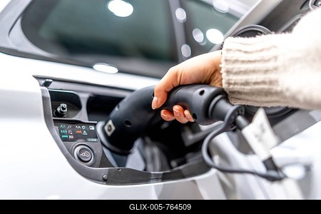 Close up of a hand plugging a charging cable into an electric vehicle at a car dealership, showcasing the transition to sustainable transportation-stock-foto
