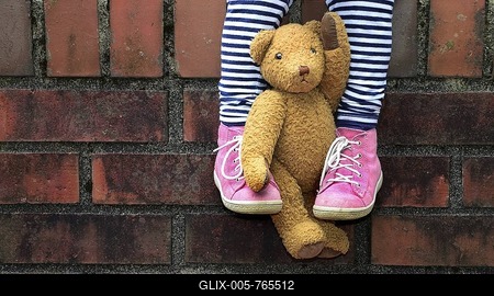 Teddy clamped between legs, child sitting on wall, detail, Germany-stock-foto