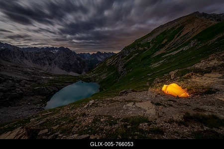 Tent in mountainous landscape with Lake Guffelsee in moonlight and cloudy sky, Gramais, Lechtal Außerfern, Tyrol, Austria-stock-foto