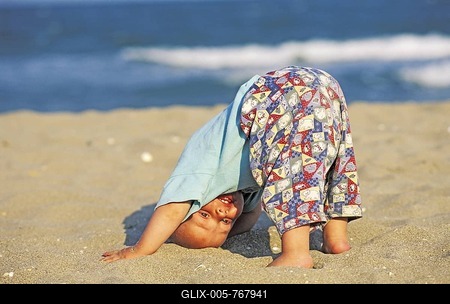 Baby making a headstand in the sand MR-stock-foto
