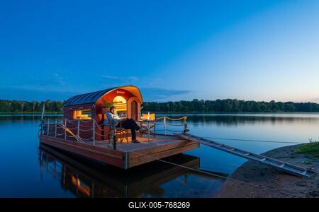 Man sitting in the blue hour on a houseboat, house raft, in front of the island Kiehnwerder, Breitlingsee, Brandenburg an der Havel, Havelland, Brandenburg, Germany-stock-foto