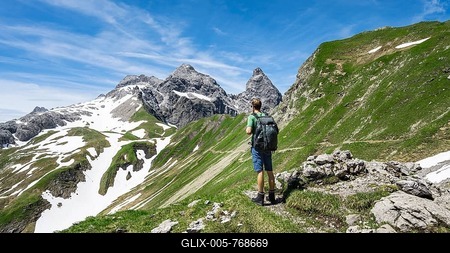Hiker on hiking trail, looking into the distance, in the background old snow fields and rocky peaks of Mädelegabel and Trettachspitze, mountain panorama, Heilbronner Weg, Allgäu Alps, Allgäu, Bavaria, Germany-stock-foto