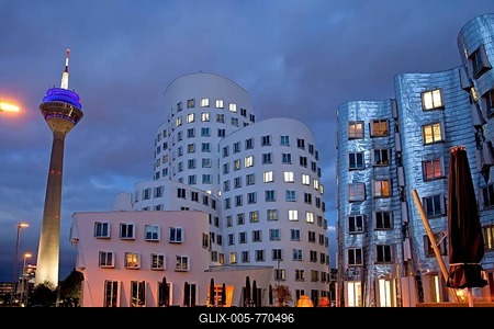 A building by American architect Frank O. Gehry and the Rheinturm tower at night, Neuer Zollhof building complex, Medienhafen district, Duesseldorf, North Rhine-Westphalia, Germany, Europe-stock-foto