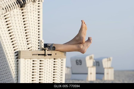 Feet protruding from a white roofed wicker beach chair on Westerland beach, Sylt island, Schleswig-Holstein, Germany, Europe-stock-foto