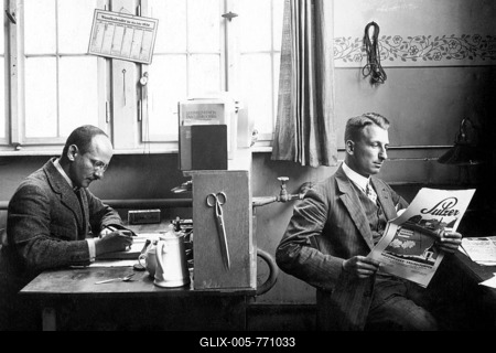 Two men in the office, one working, one reading newspaper, 1926, exact location unknown, Germany-stock-foto