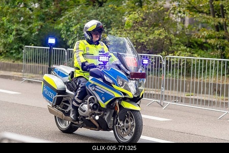 A police officer rides a motorbike with blue lights during an operation, surrounded by barriers on a road, Stuttgart, Baden-Württemberg, Germany-stock-foto