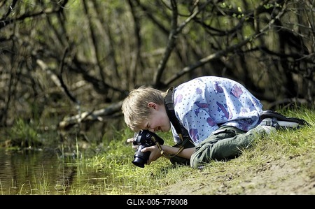 10 year old boy observing life in the water and photographing on a pond edge-stock-foto