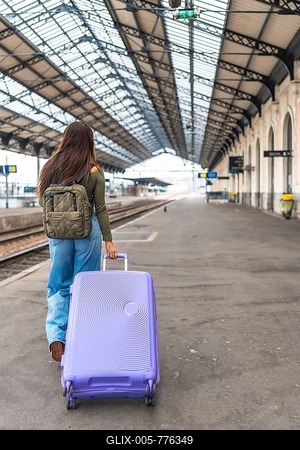 Tourist walking along a train platform, pulling a trolley suitcase while embarking on an exciting travel adventure-stock-foto