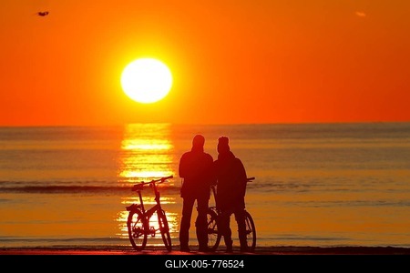 Couples with bikes on the beach watching the sunset, North Sea, St. Peter-Ording, North Sea coast, Schleswig-Holstein Wadden Sea National Park, Schleswig-Holstein, Germany-stock-foto