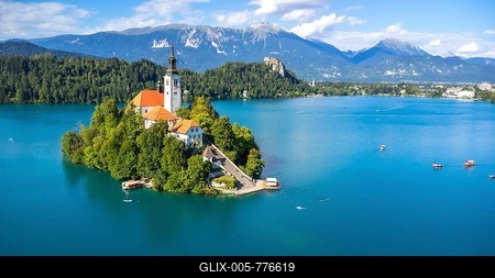 Aerial view of lake bled island with pilgrimage church of the assumption of maria on a sunny summer day with julian alps and bled castle in the background-stock-foto