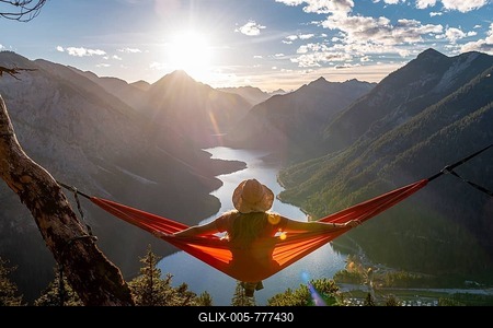 Woman with a sun hat sitting in an orange hammock, panoramic view of mountains with lake, Plansee, Tyrol, Austria-stock-foto