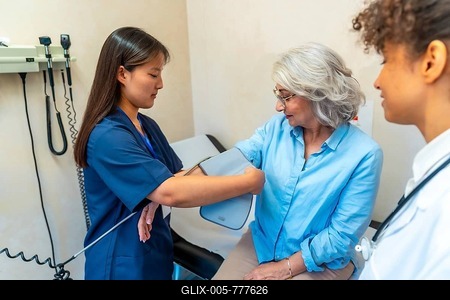 Nurse using sphygmomanometer, taking blood pressure of elderly woman during medical consultation in hospital or private clinic-stock-foto