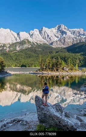 Hiker stands on rocks, looks into the distance, Lake Eibsee lake and Zugspitze, Wetterstein range, near Grainau, Upper Bavaria, Bavaria, Germany-stock-foto