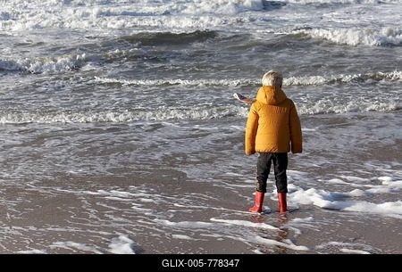 Little boy in winter clothes standing in the surf on the beach, sea view, North Sea, Netherlands-stock-foto