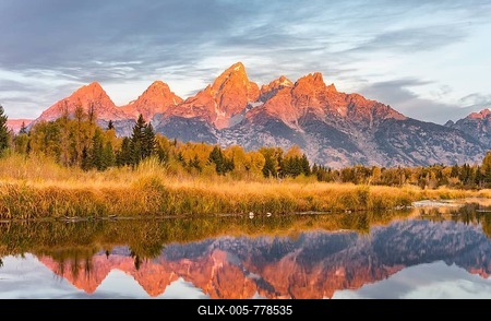 Mountains glow red at sunrise, Grand Teton Range mountain range reflected in the river, autumn landscape on Snake River, Schwabacher Landing, Grand Teton National Park, Wyoming, USA-stock-foto