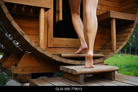 Low angle view of female bare feet going up the stairs of outdoor barrel-shaped wooden sauna-stock-foto