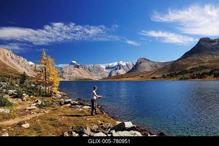 A fisherman with a fishing rod is standing on the banks of Ptarmigan Lake, Rocky Mountains, Banff National Park, Alberta, Canada-stock-foto