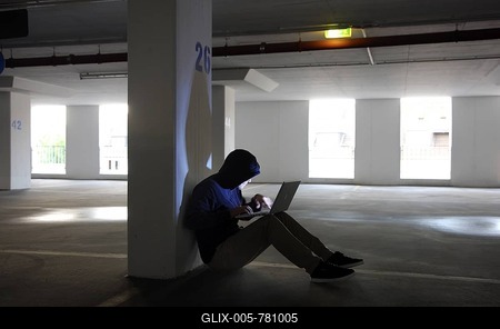 Man surfing on a laptop computer in an empty multi-storey car park, symbolic image for computer hacking, computer crime, cybercrime, data theft-stock-foto