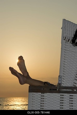 Roofed wicker beach chair and bare feet at sunset, Westerland, Sylt island, Schleswig-Holstein, Germany, Europe-stock-foto
